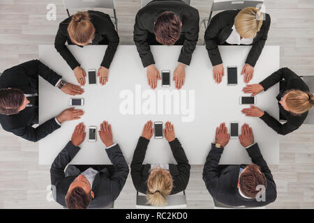Business people not using smartphones sitting around white table Stock Photo