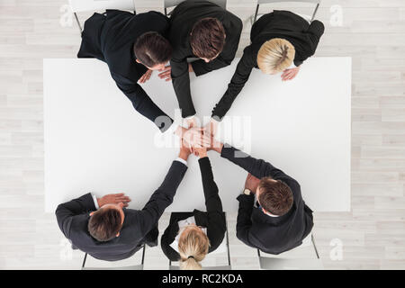 Directly below shot of business team stacking hands over white table background Stock Photo