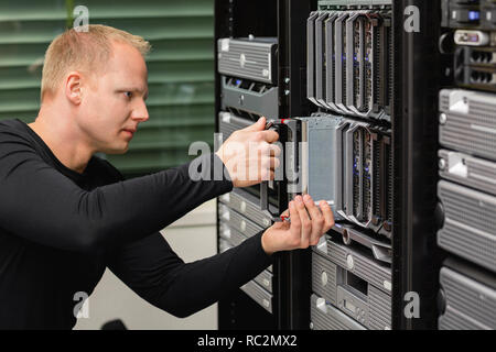 Male Technical Consultant Replacing Blade Server In SAN At Datacenter Stock Photo