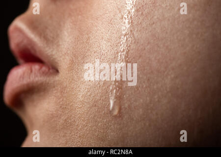 sad woman cries, shot a close up of female cheek with a tear drop Stock Photo