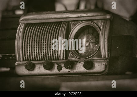 Old vintage radio receiver of the last century with rustic clock build in, on shelf - front view, sepia style photography Stock Photo