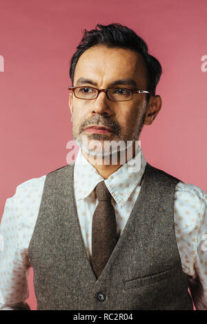 Portrait of a mature man in vest and glasses, isolated on pink Stock Photo