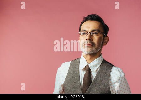 Portrait of a mature man in vest and glasses, isolated on pink Stock Photo