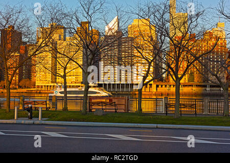 East River waterway and Manhattan skyline at sunrise in New York, USA. Urban panorama in golden hues of early morning in winter. Stock Photo