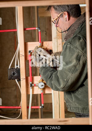 Plumber using pliers on some plastic pipes Stock Photo