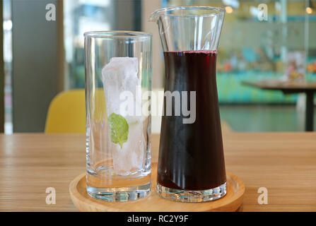 A Carafe of Roselle Juice with a Glass of Ice Cube on Wooden Tray Served on Wooden Table Stock Photo