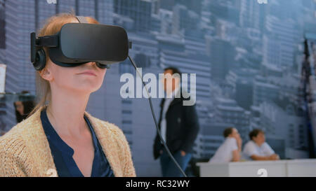 Virtual reality game. Young woman using virtual reality glasses at urban exhibition. Education, VR and technology concept Stock Photo