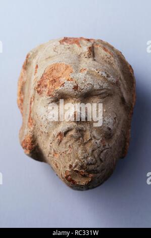 Terracotta antefixes representing a bearded head with clear slip .Height 7, 2 cm Width 5, 7 cm Thickness 4 , 2 cm ( 1 st - 5 th CE ) - Roman period from the necropolis of ' Villa del Val ' - Archaeological site of Complutum in Alcalá de Henares ( Madrid ). SPAIN. Stock Photo