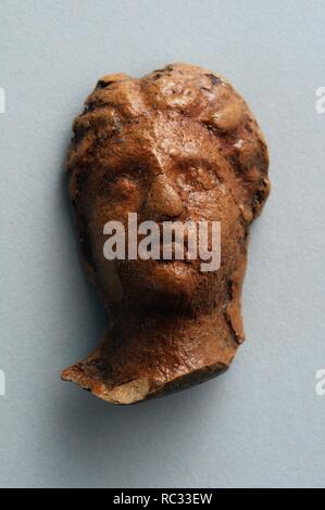 Head female of terracotta figurine with roman hairstyle. Height 3.6 cm Width 2, 3 cm (1 st - 3 rd CE ) - Roman period from  ' House of Hyppolytus '- Archaeological site of Complutum in Alcalá de Henares ( Madrid ). SPAIN. Stock Photo