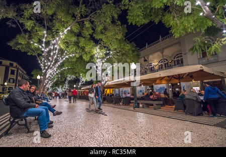 People walking along the tree lined avenue 'Avenida Arriage' in Funchal, Madeira at night. Stock Photo