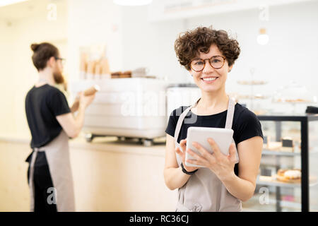 Smiling pretty waitress using tablet to take order Stock Photo