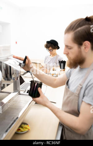 Waitress writing down orders while barista making coffee Stock Photo