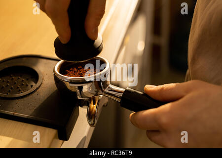Pressing ground coffee into portafilter Stock Photo