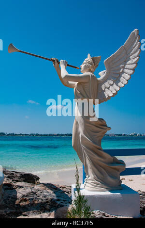 White sculpture of an angel holding  trumpet with the blue sky in the background, outdoors, sunny day. Stock Photo