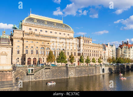 Prague National Theatre Národní divadlo on the banks of the river Vltava with people on the river in boats Prague Czech Republic EU Europe Stock Photo