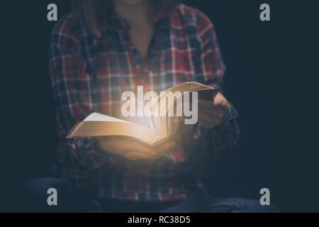 Young woman readin bible in a dark room Stock Photo