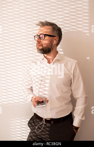 Pensive handsome businessman in earphones Stock Photo