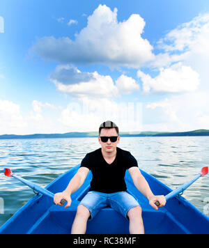 Stylish  young man portrait with sunglasses. Boat ride on a summer day on the lake. Stock Photo