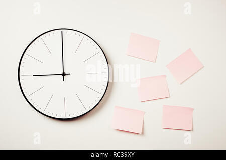 Wall clock and pink stickers on white background. Workspace mock up Stock Photo