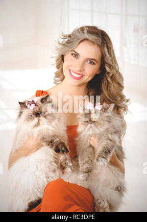 Portrait of elegant young woman holding two adorable Persian cats Stock Photo