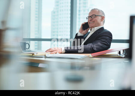 Businessman Working In Office With Computer And Talking On Phone Stock Photo