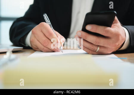 Hands Of Business Man Writing With Pen And Holding Phone Stock Photo