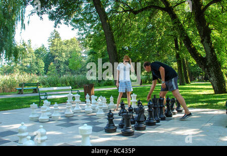 Father and son outdoors playing in large outdoor chess Stock Photo