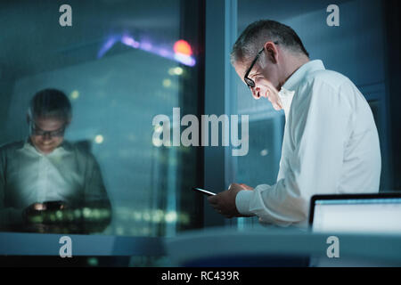 Happy Manager Using Smartphone In Dark Office At Night Stock Photo