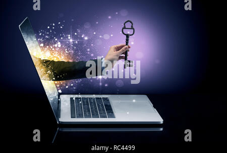 Hand with huge vintage key coming out of a laptop with sparkling effects  Stock Photo