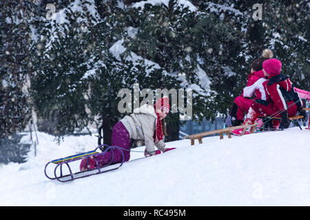 Nis, Serbia - January 12, 2019 Young girl with sled enjoying on snow in hills city park on winter day in warm clothes. Winter game and recreation Stock Photo