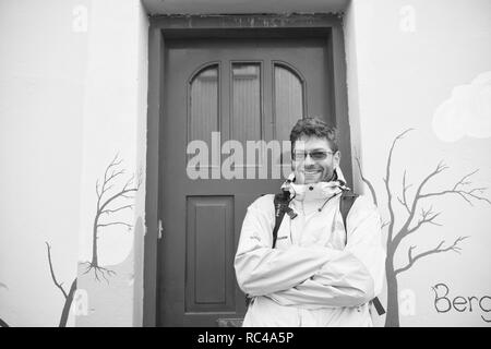 Reykjavik, Iceland - October 12, 2017: happy man tourist. Active man stand at house door. Tourist agency. As happy as a clam. Travel more get happy, Stock Photo