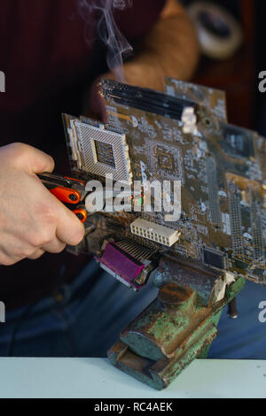 Repair motherboard. Service technician changes the capacitor. Troubleshooting. Man unrecognizable Stock Photo
