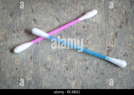 Multi colour cotton swab used for cleaning ears kept on a textured grey table Stock Photo