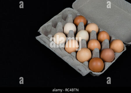 Twelve chicken eggs in a carton box, isolated on black felt background. Stock Photo