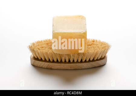 Piece of Marseille soap, made of vegetable oil, sitting on bathing brush, isolated on white background with shadow Stock Photo