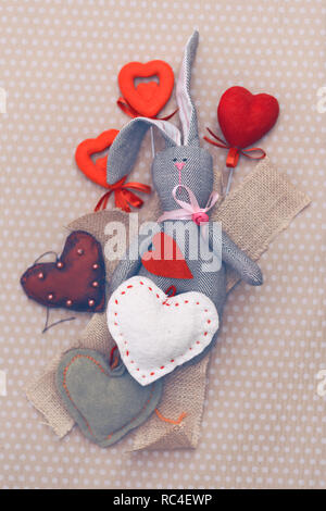 Valentines day. Tilde rabbit lying in a pile of handmade hearts