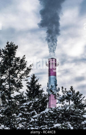 Industrial chimneys with dramatic smoke in nature on cold winter day. Factory pipe polluting air, smoke from chimneys in clouds. Ecological concept Stock Photo