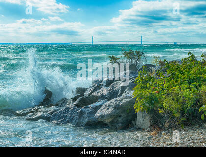 Waves crashing on Mackinac Island rocks with Mackinac Bridge in background Stock Photo