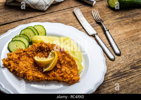 Chicken fried schnitzel with mashed potatoes and lemon on wood table Stock Photo