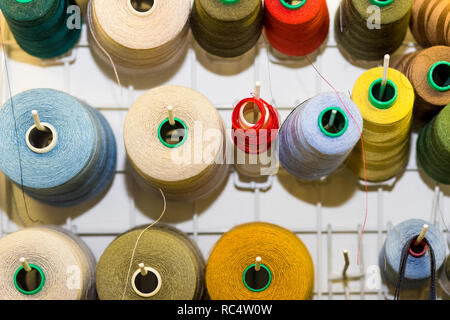 Bobbins with colorful threads on old wooden table background, Sewing background.Interior of sewing workshop.technology, material, equipment, Hobby concept.spools of thread. Stock Photo