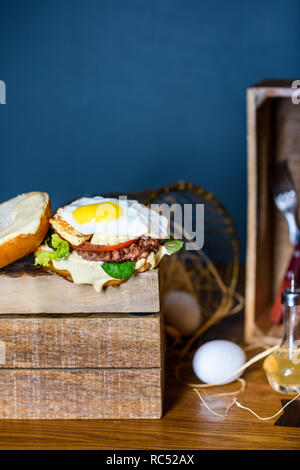 Burger with beef, egg and cheese. French fries with rosemary. Close up, copy space. Stock Photo
