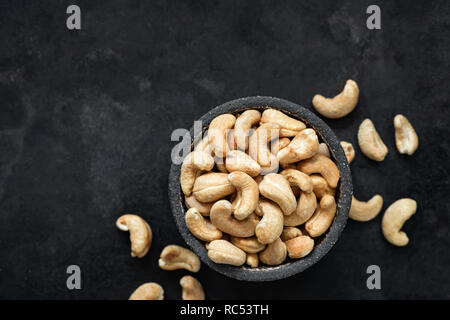 Cashew nuts in bowl on black background. Top view, copy space for text. Healthy snack, vegetarian food, beer snack Stock Photo