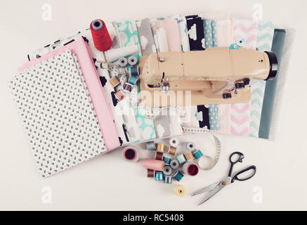 top view of cotton fabric material for tailor or homework, sewing concept with sewing machine, white tailor's meter, threads and scissors Stock Photo