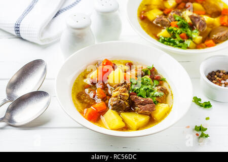 Traditional German eintopf soup with meat, beans and vegetables in a white plate. Stock Photo