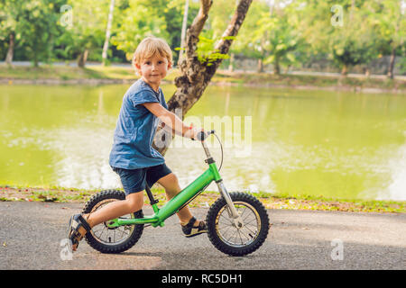 Little boy on a bicycle. Caught in motion, on a driveway. Preschool child's first day on the bike. The joy of movement. Little athlete learns to keep balance while riding a bicycle Stock Photo