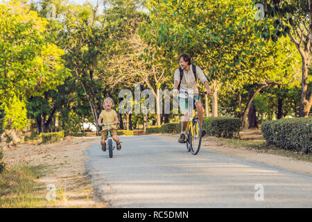 Happy family is riding bikes outdoors and smiling. Father on a bike and son on a balancebike Stock Photo