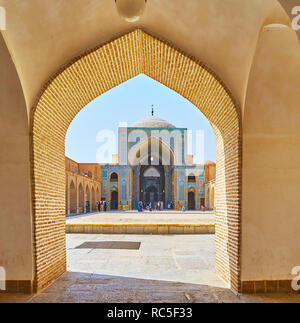 YAZD, IRAN - OCTOBER 18, 2017: Walk along the arcade of Jameh Mosque with a vew on its main tiled portal and scenic dome, on October 18 in Yazd. Stock Photo