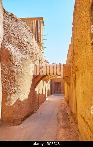 The lazy walk in medieval adobe town with a view on traditional desrt architecture with tall blank walls, kuche passageways and windcatchers (badgirs) Stock Photo