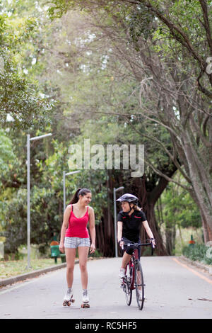 https://l450v.alamy.com/450v/rc5hf5/two-young-women-one-on-roller-skates-and-another-on-a-bicycle-talking-in-ibirapuera-park-sao-paulo-brazil-rc5hf5.jpg