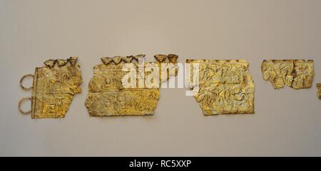 Cultura Castreña. Diadema-cinturón de Moñes. Oro. Siglos III-I a. C. Se representa, en un paisaje acuático, personajes llevando calderos y jinetes con torques-sonajeros y escudos o puñales. Representa el tránsito a la otra vida. Procedente de Moñes (Piloña, Asturias). A la izquierda, fragmentos originales. A la derecha, réplica de fragmentos en el Museo de Arqueología Nacional y Dominio Nacional de Saint-Germain-en-Laye y en el Instituto Valencia de Don Juan, Madrid. Museo Arqueológico Nacional. Madrid. España. Stock Photo